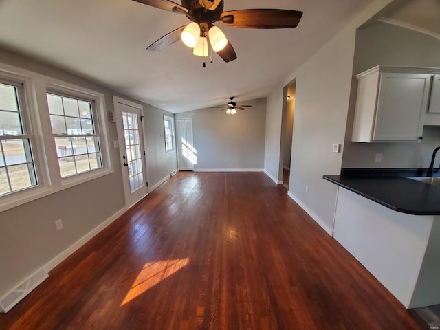 unfurnished living room with lofted ceiling, baseboards, visible vents, and dark wood finished floors