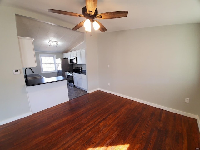 kitchen featuring dark wood-style flooring, stainless steel appliances, dark countertops, white cabinetry, and a sink