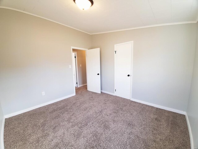 empty room with ornamental molding, carpet flooring, and baseboards