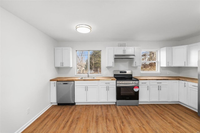 kitchen with stainless steel appliances, light wood-style flooring, a sink, wood counters, and under cabinet range hood