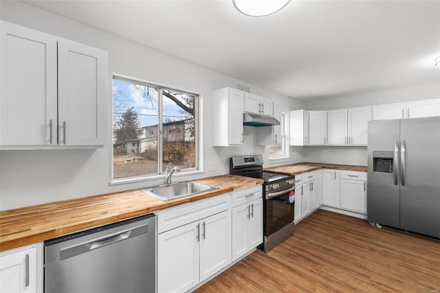 kitchen with stainless steel appliances, light wood-style floors, a sink, butcher block countertops, and under cabinet range hood