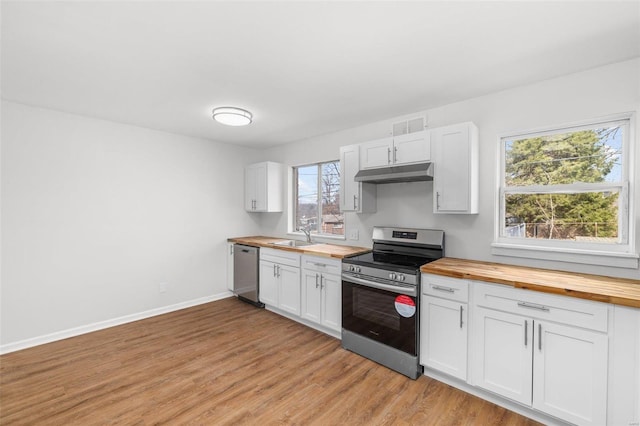 kitchen with under cabinet range hood, stainless steel appliances, butcher block countertops, a sink, and light wood-style floors