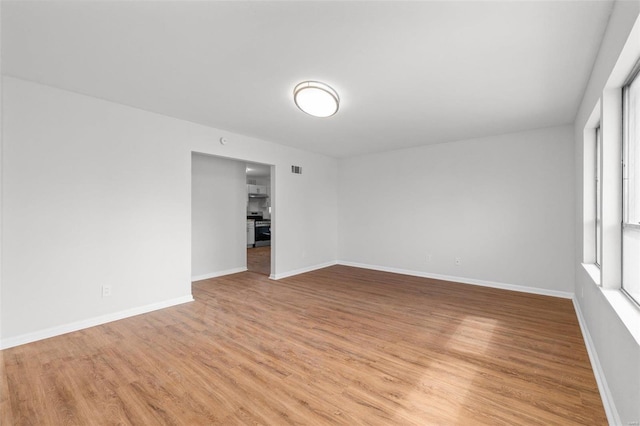 unfurnished room featuring light wood finished floors, visible vents, and baseboards