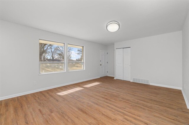 unfurnished bedroom with light wood-type flooring, visible vents, and baseboards