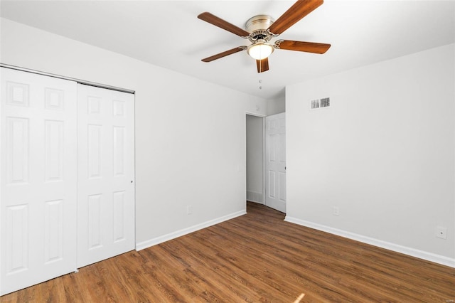 unfurnished bedroom with a closet, visible vents, baseboards, and wood finished floors