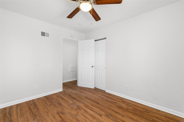 unfurnished bedroom with a closet, wood finished floors, visible vents, and baseboards