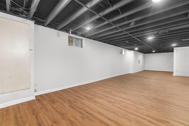 basement with a healthy amount of sunlight, baseboards, and wood finished floors