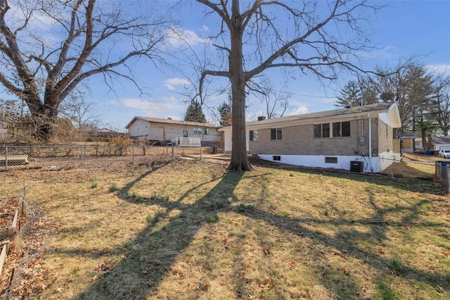 back of property with a lawn, central AC unit, and fence