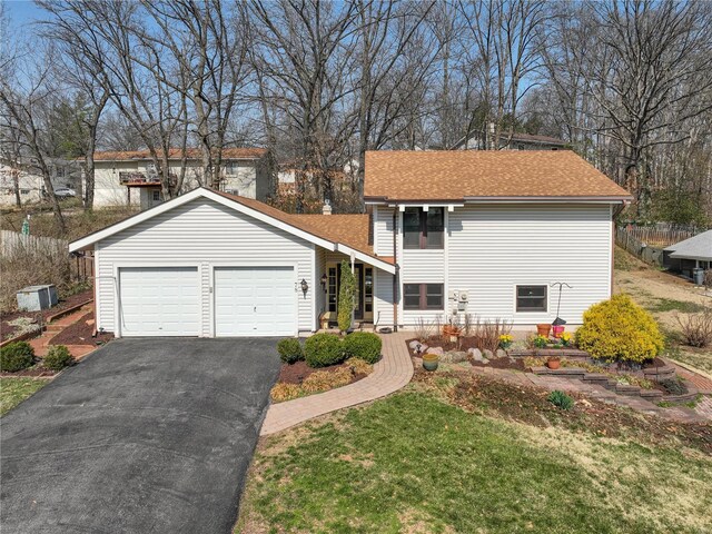 view of front facade featuring aphalt driveway, a front lawn, roof with shingles, and an attached garage