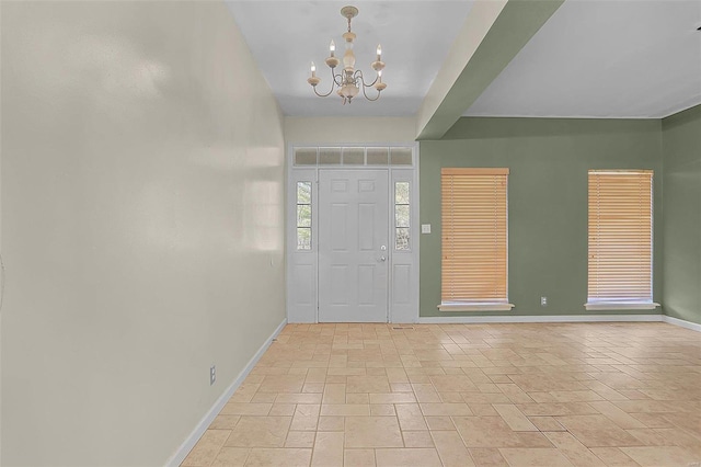 entrance foyer featuring stone finish floor, an inviting chandelier, and baseboards