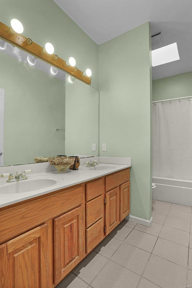 full bath featuring tile patterned flooring, a sink, a skylight, and double vanity