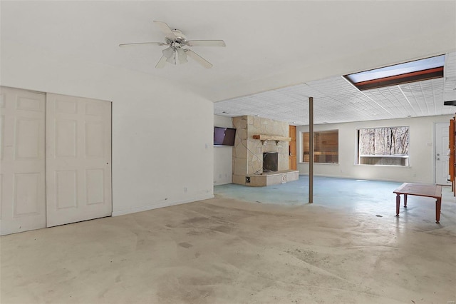 basement featuring baseboards, ceiling fan, and a fireplace