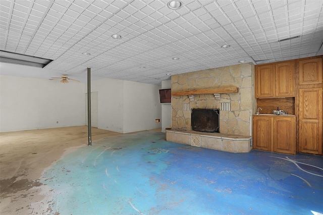 unfurnished living room with a stone fireplace and unfinished concrete floors