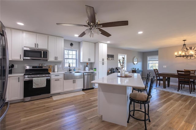 kitchen featuring appliances with stainless steel finishes, a center island, light countertops, and a sink