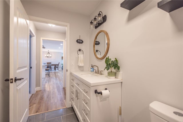 half bathroom featuring toilet, wood finished floors, and vanity