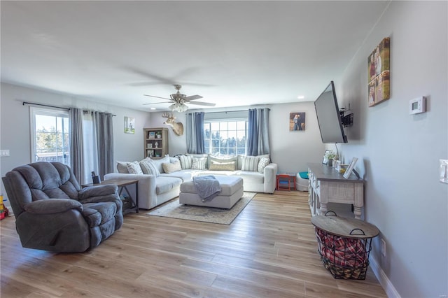 living room featuring a ceiling fan, light wood-style flooring, and baseboards