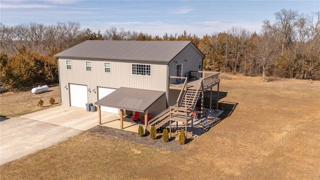 view of front of house featuring a garage, metal roof, driveway, and stairs