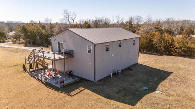 view of side of home featuring a deck, a patio, metal roof, cooling unit, and stairway