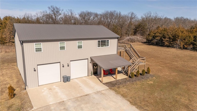 view of front facade with a garage, metal roof, driveway, and stairs