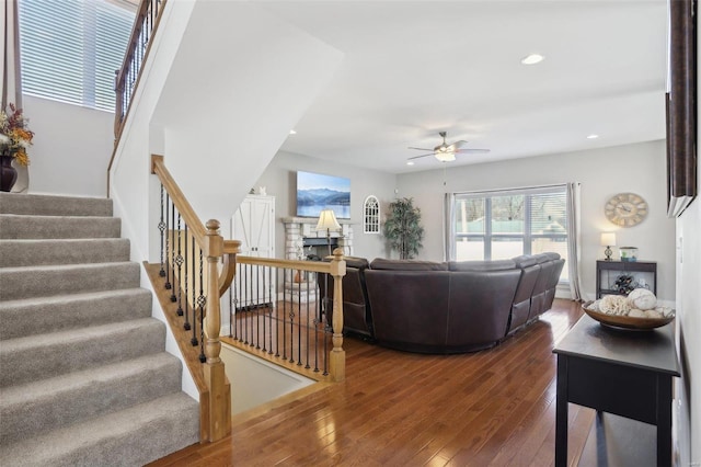 living room featuring a ceiling fan, dark wood-style floors, recessed lighting, stairway, and a fireplace