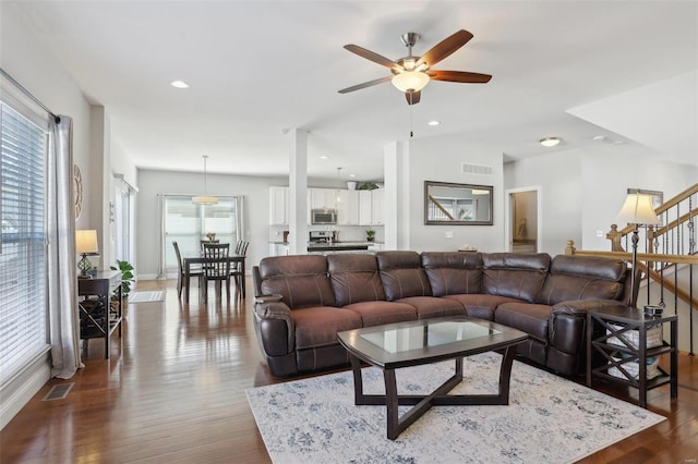 living area with dark wood finished floors, visible vents, recessed lighting, and stairs