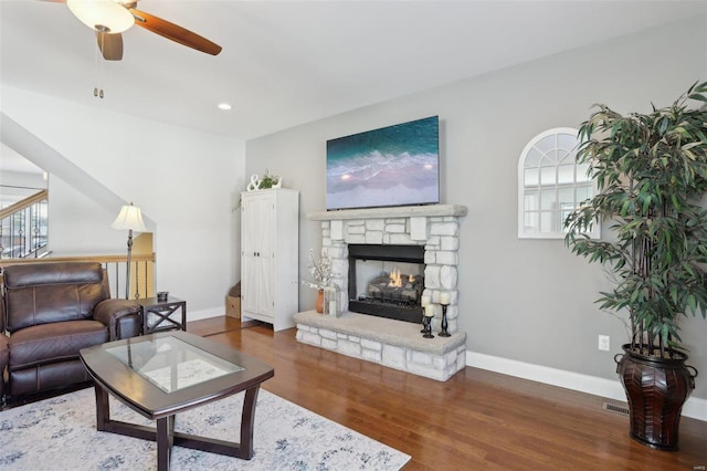 living area featuring baseboards, plenty of natural light, wood finished floors, and a fireplace