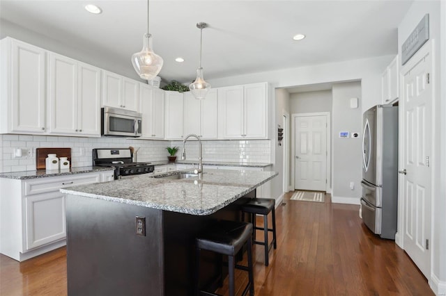 kitchen featuring a sink, dark wood finished floors, light stone countertops, and stainless steel appliances