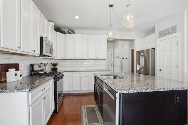 kitchen with light stone countertops, a sink, dark wood-type flooring, appliances with stainless steel finishes, and tasteful backsplash