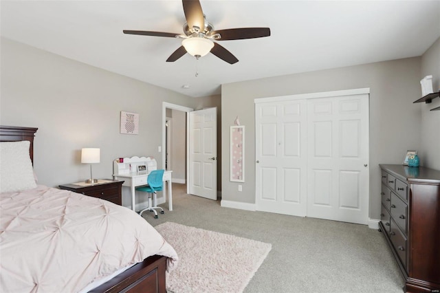 bedroom featuring a closet, baseboards, light colored carpet, and ceiling fan