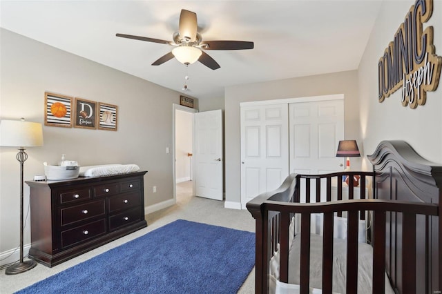 carpeted bedroom featuring a closet, baseboards, and a ceiling fan