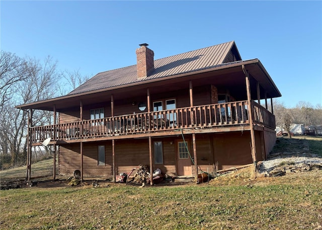 rear view of house with a chimney, metal roof, a standing seam roof, a yard, and a wooden deck