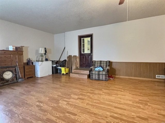 miscellaneous room featuring a textured ceiling, wainscoting, wood finished floors, and visible vents