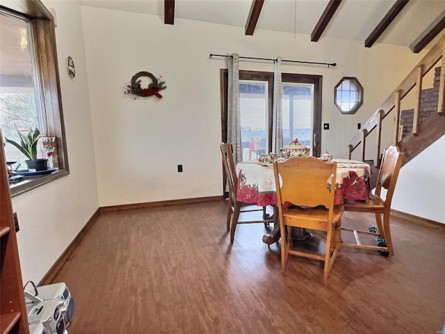 dining area with beam ceiling, baseboards, and wood finished floors