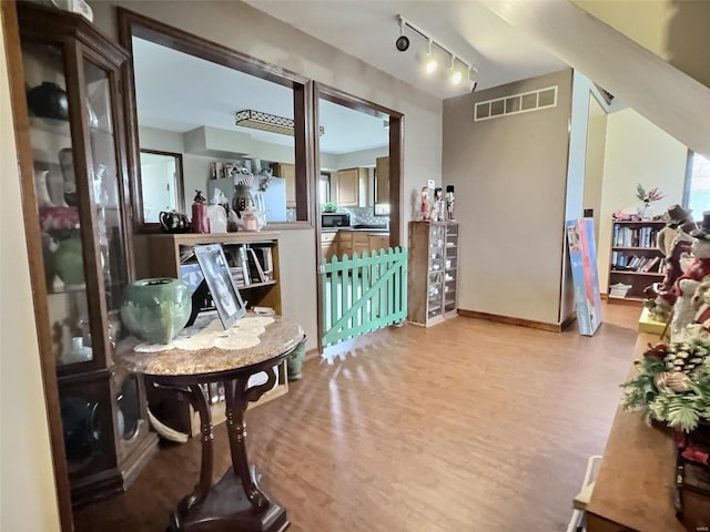 interior space featuring rail lighting, baseboards, visible vents, and wood finished floors