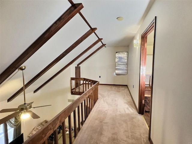 hallway featuring a healthy amount of sunlight, light carpet, lofted ceiling with beams, and an upstairs landing