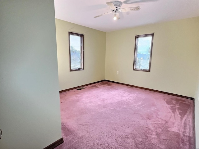 carpeted spare room featuring a wealth of natural light, visible vents, and baseboards