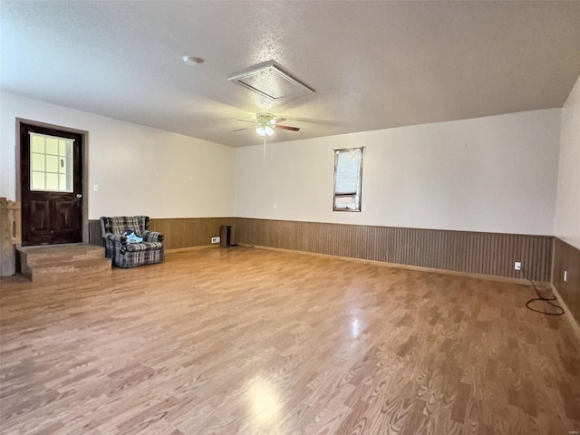 spare room with wooden walls, wood finished floors, and wainscoting