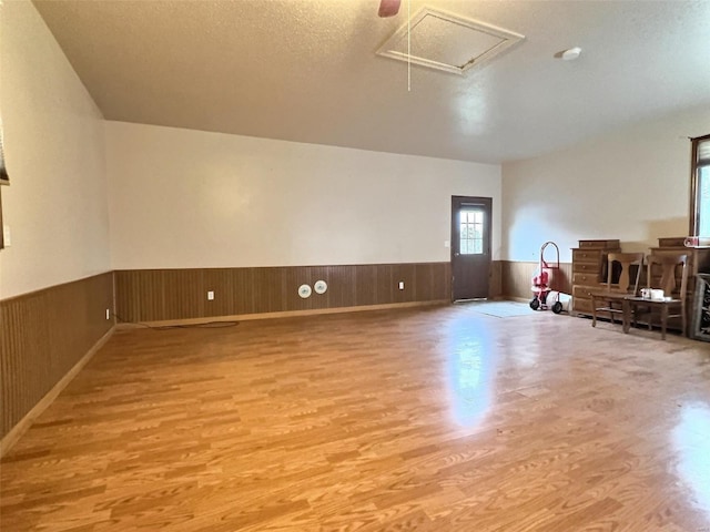 interior space with wainscoting, wood finished floors, and attic access