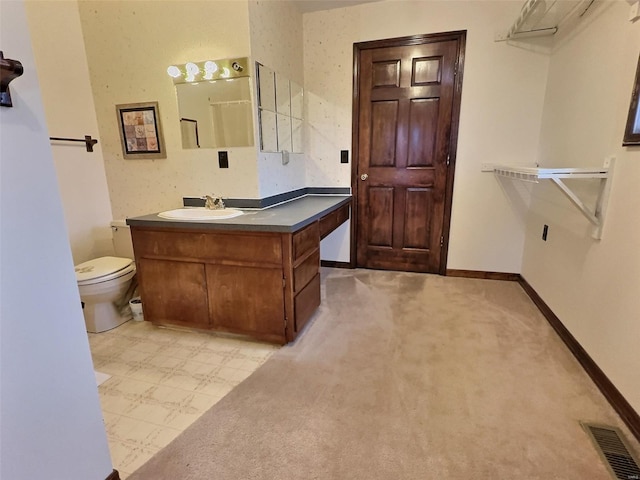 bathroom with toilet, vanity, visible vents, and baseboards