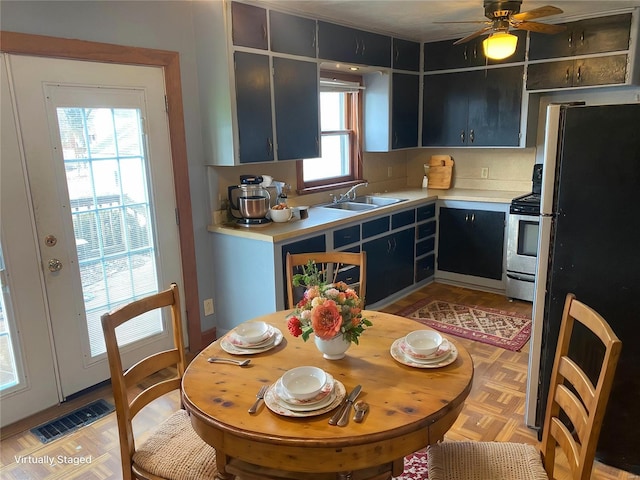 kitchen with a sink, visible vents, light countertops, stainless steel range with gas cooktop, and freestanding refrigerator