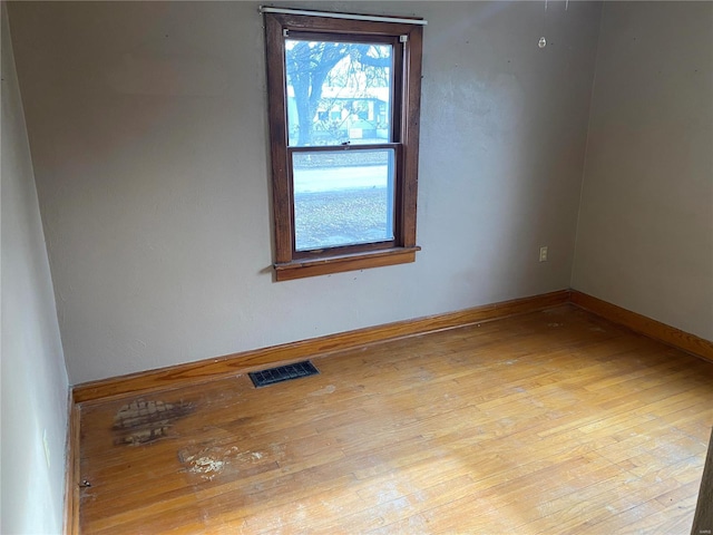 unfurnished room featuring visible vents, baseboards, and hardwood / wood-style flooring