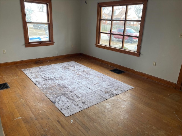 unfurnished room with hardwood / wood-style flooring, baseboards, and visible vents