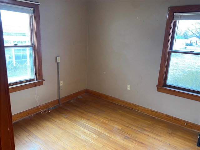 empty room featuring light wood-type flooring, a healthy amount of sunlight, and baseboards