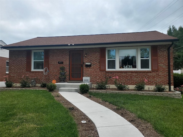 view of front of property with a front yard, brick siding, and roof with shingles