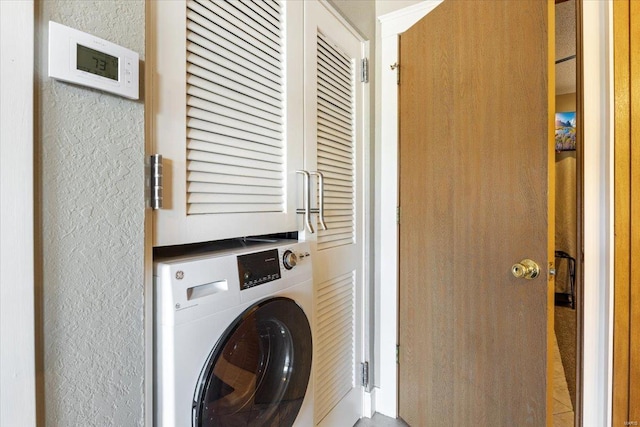 washroom with washer / dryer, laundry area, and a textured wall