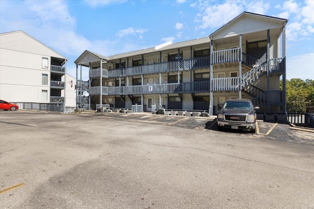 view of property with stairs and uncovered parking