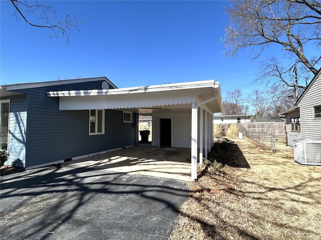 view of property exterior featuring driveway, central air condition unit, fence, and a carport