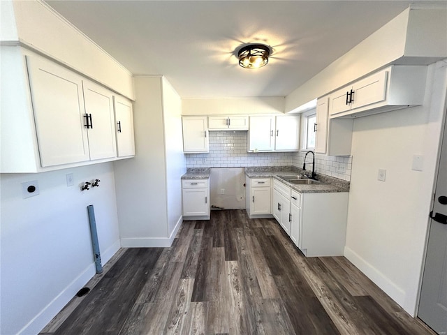 kitchen featuring dark wood-style flooring, backsplash, a sink, and baseboards