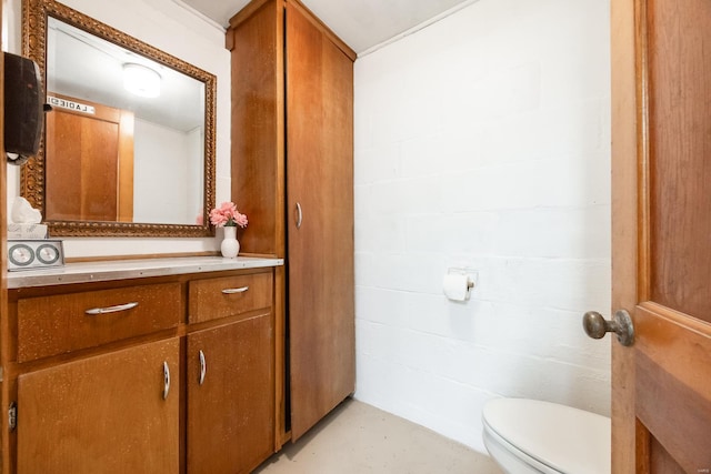 bathroom with vanity, concrete block wall, and toilet