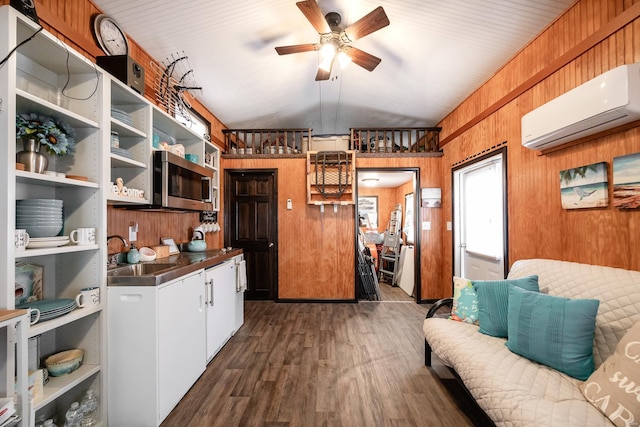 kitchen featuring a wall mounted AC, a sink, stainless steel microwave, dark wood-style floors, and wood walls